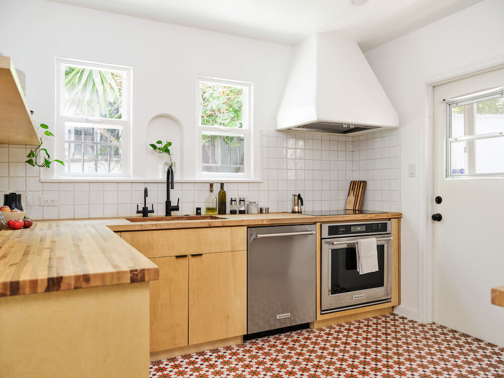 Kitchen with plywood cabinets, Moroccan floor tiles, plastered oven range and white wall tile