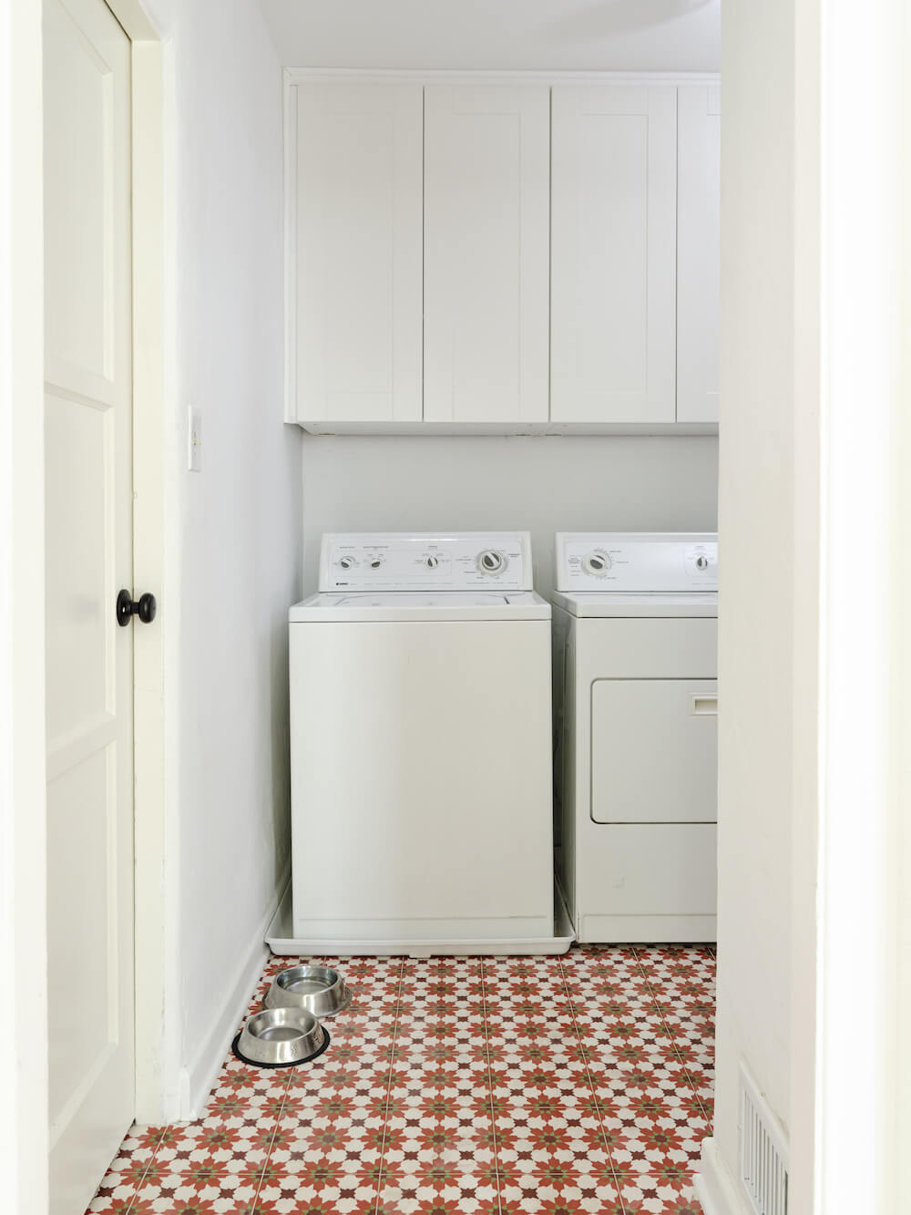 Laundry room with Moroccan floor tiles, white cabinets and white washer and dryer