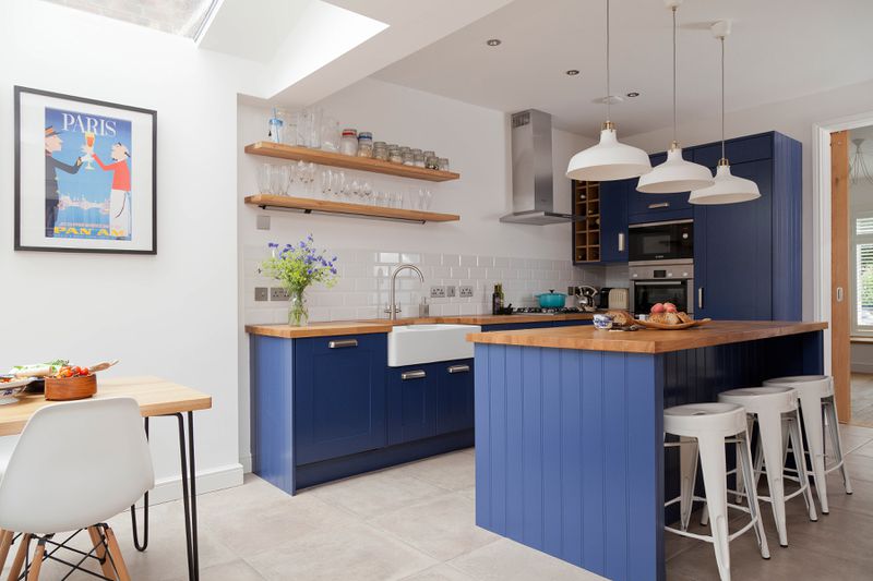 A small kitchen with a blue painted island that allows the space to be more open than a traditional galley kitchen. 