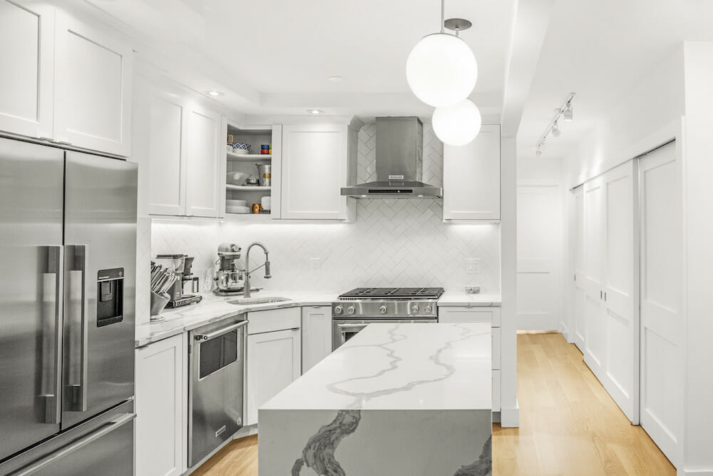 Kitchen with white Shaker-style cabinets, white quartz countertops and metal refrigerator and stove
