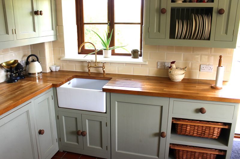 The corner of a kitchen with a small farmhouse sink and a wood countertop.
