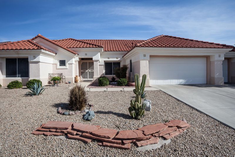 A Southwestern home with a rock front yard, a small slate wall and desert vegetation. 