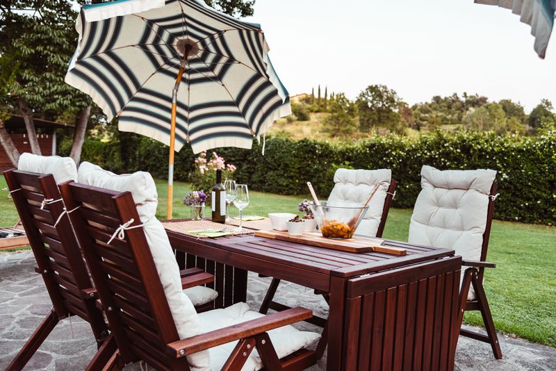 An outdoor patio with a seating area and a tilted umbrella to provide shade. 