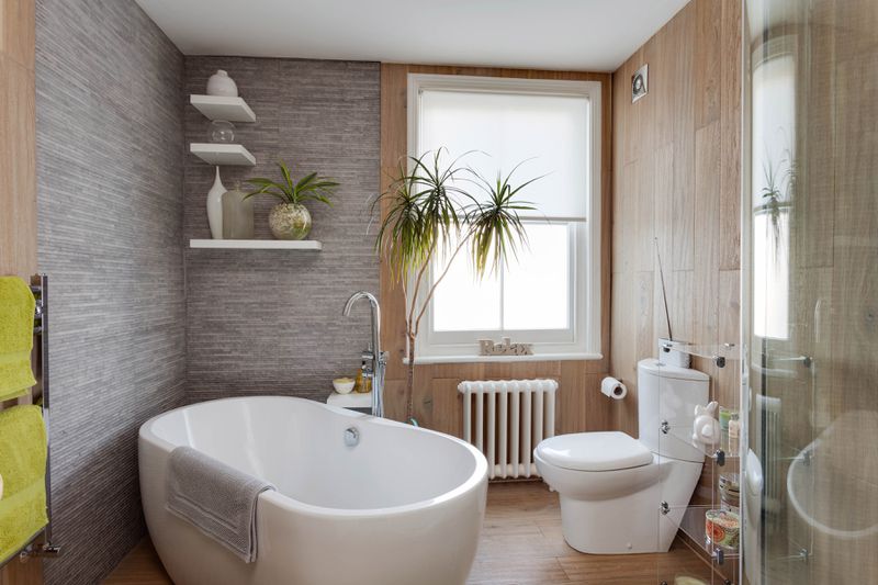 A bathroom with free standing tub and wood laminate floors. 