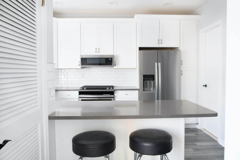 Image of a kitchen peninsula with black bar stools facing into the kitchen area