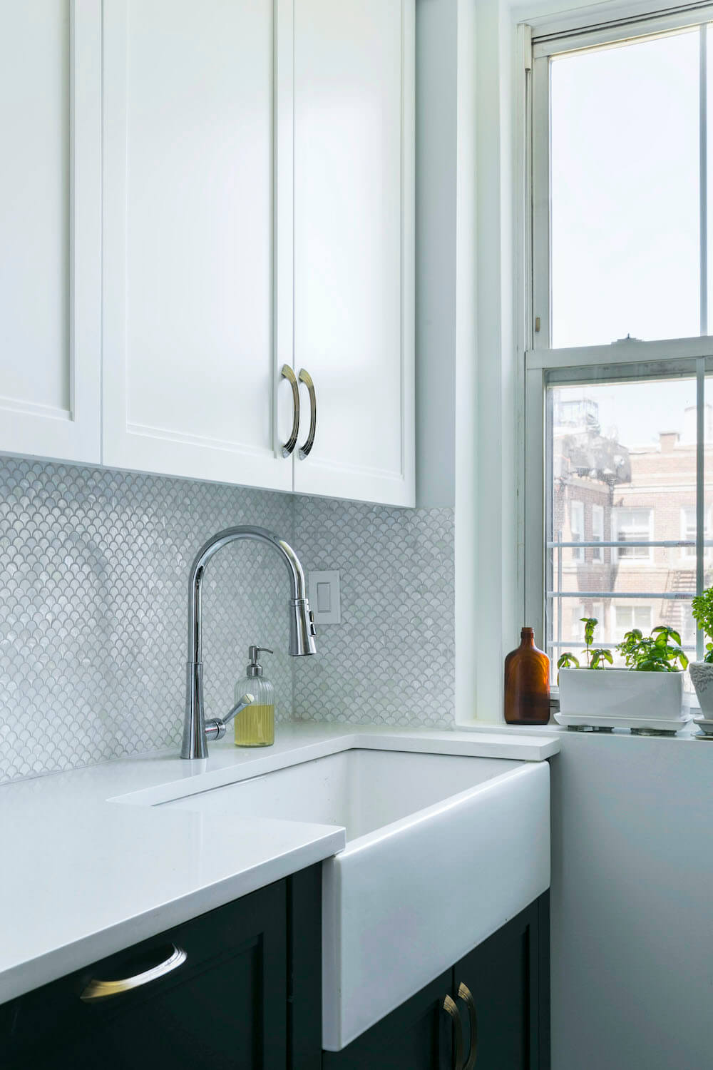 Kitchen sink with white countertops and cabinets and tiled backsplash