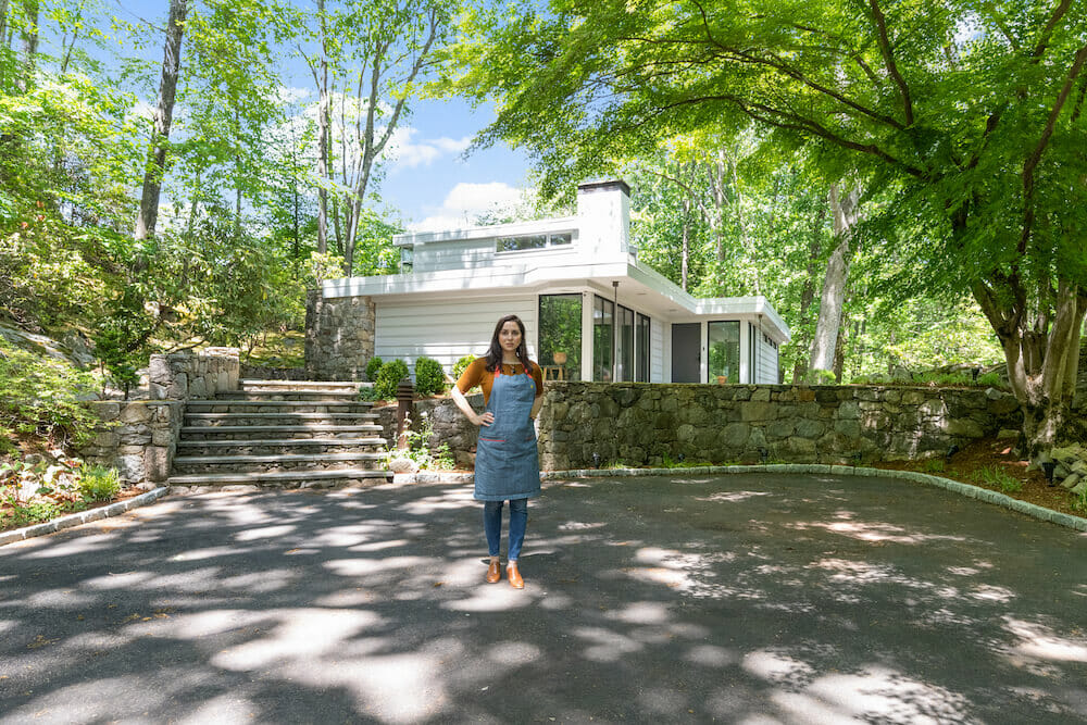 Homeowner standing in her driveway in front of a white modern house