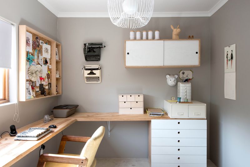 A gray office with a natural wood corner desk and white accents.