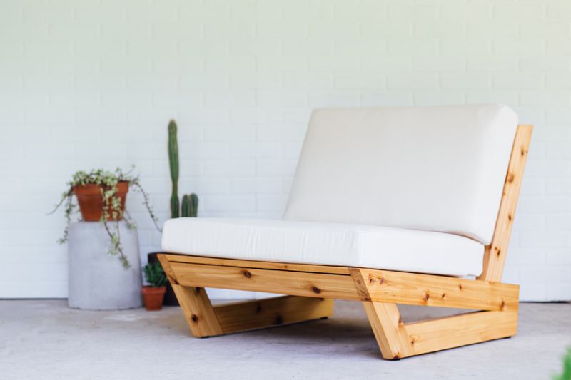 A modern wood lounge chair with white cushions.  