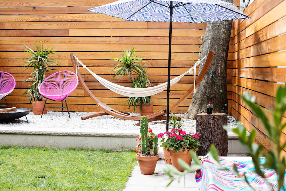 Image of a remodeled backyard with gravel lounge area and umbrella and hammock