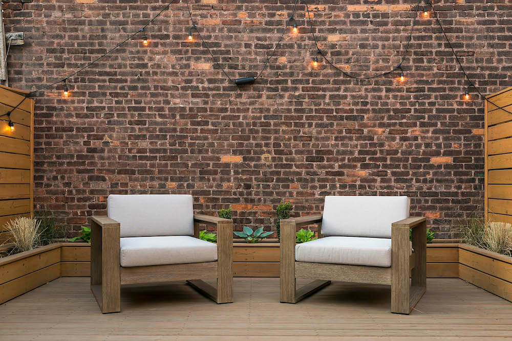 Image of two outdoor chairs with exposed brick wall
