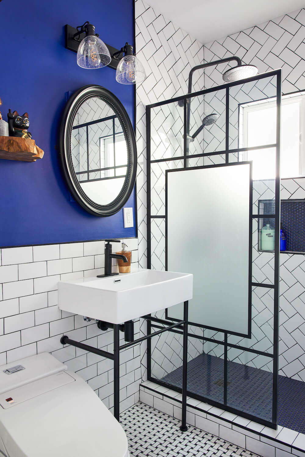 Image of a renovated bathroom with blue accent wall, white sink and subway tile