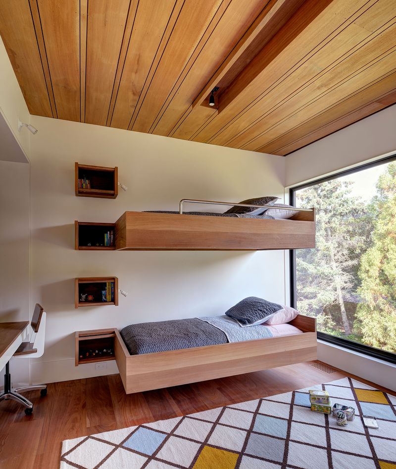 Modern wooden bunk beds with a floating bookcase that also functions as a ladder.