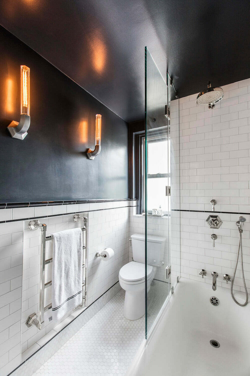 Image of renovated bathroom with towel warmer, subway tile and black accent walls