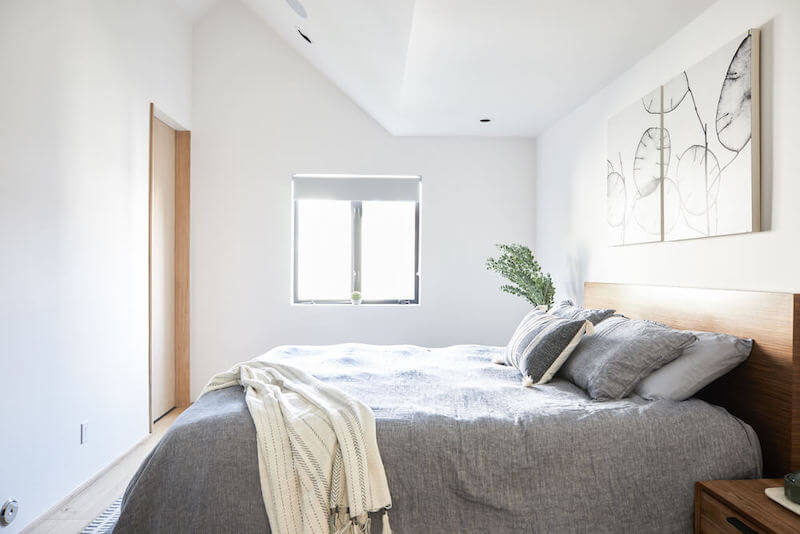 Minimalist master bedroom with slanted white ceiling and walls