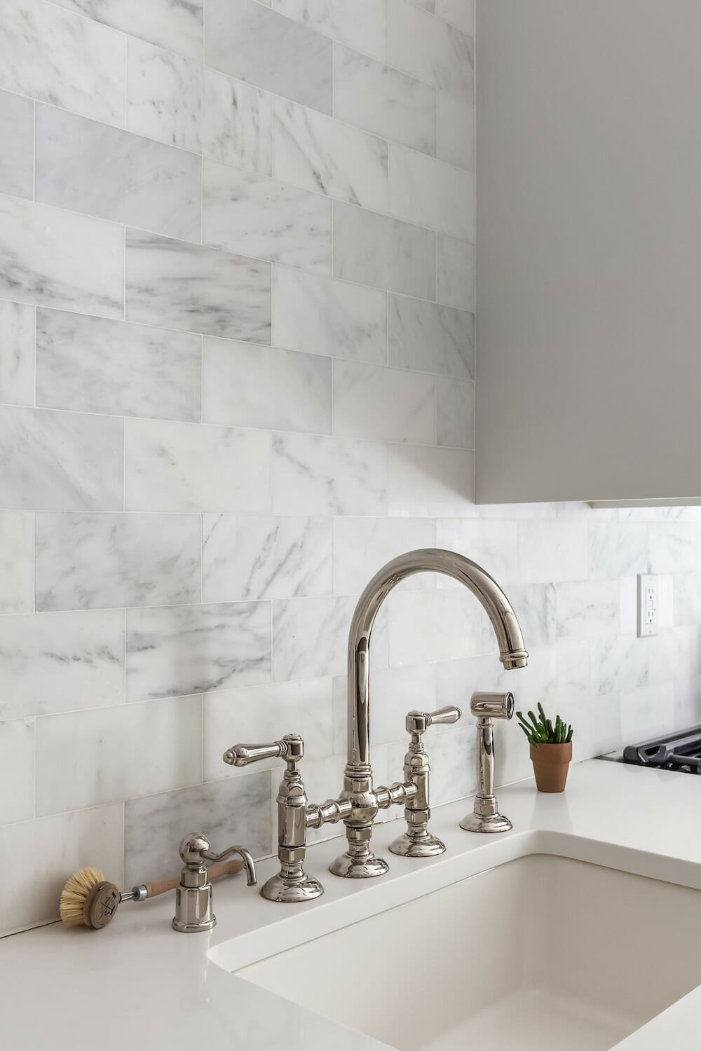 Image of a kitchen sink with Carrara marble backsplash