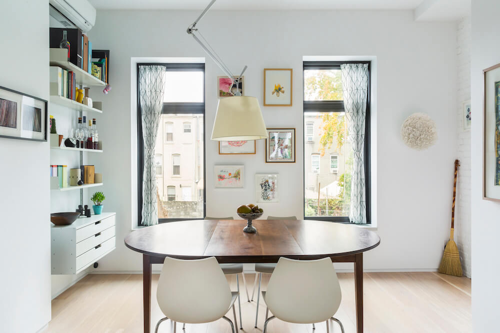 Image of a dining area with wooden dining table, chairs and wall shelves