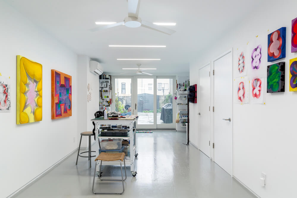 Image of an at-home basement art studio with hanging art on the walls