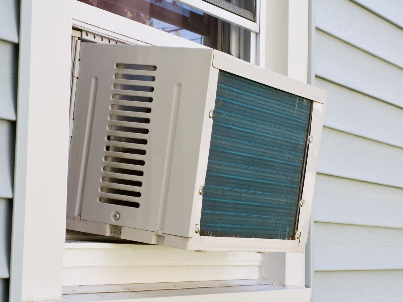 The exterior of a house with a brand new AC unit in the window. 
