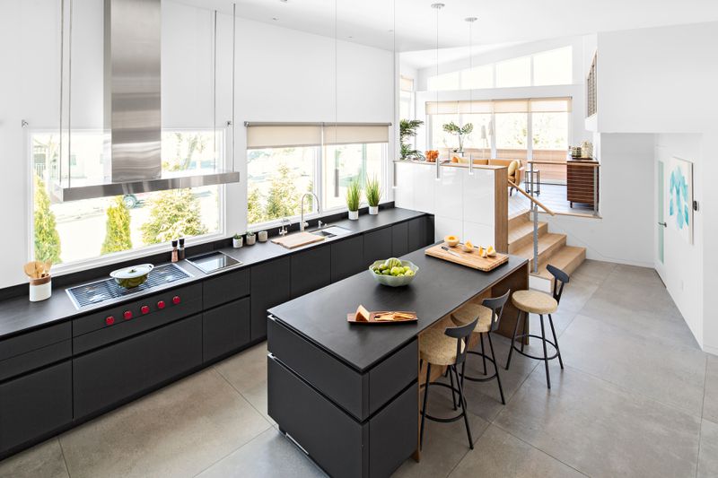 A modern kitchen with white walls and black flat-front cabinets. 