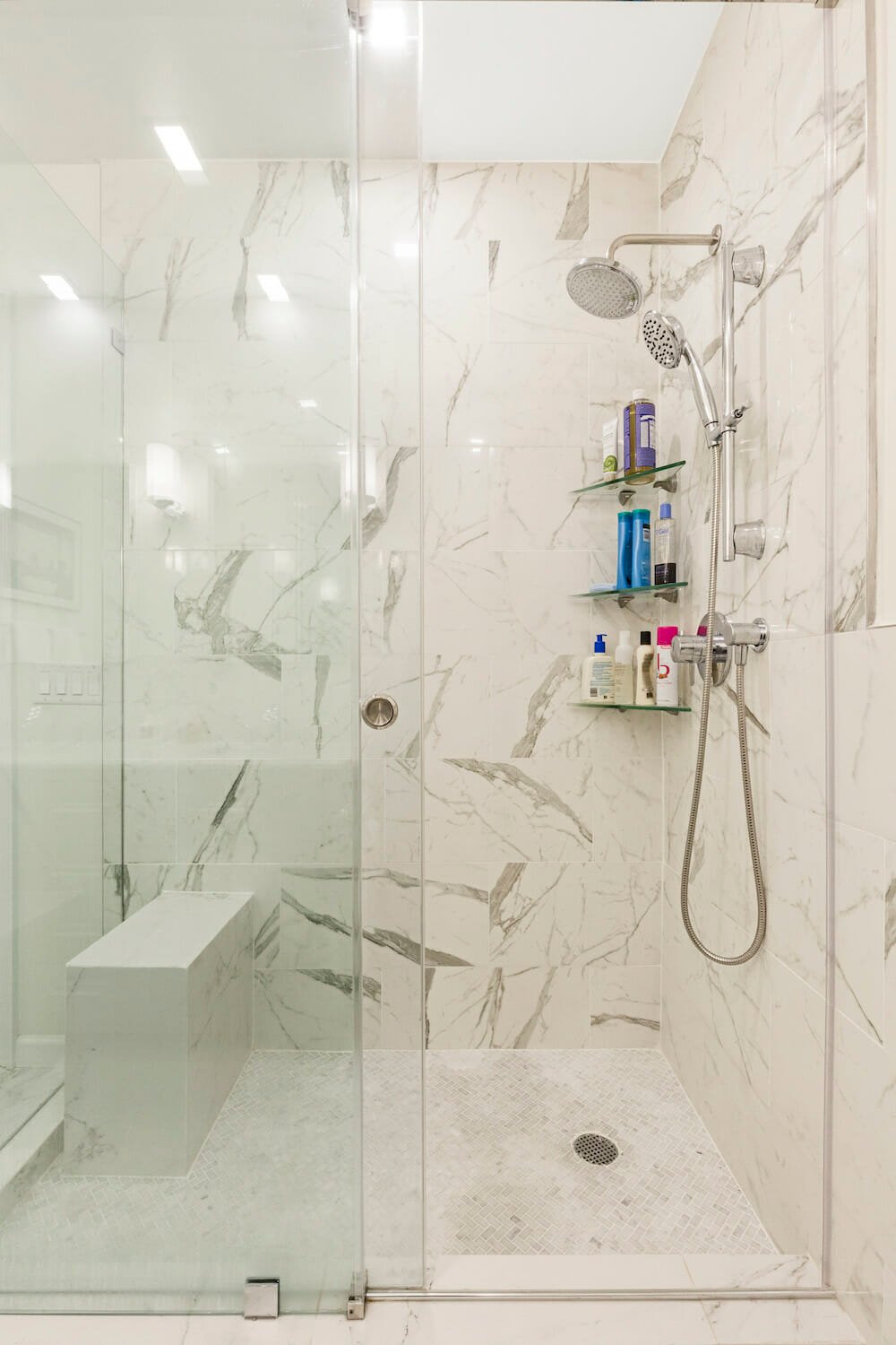frameless glass sliding doors to a walk in shower with steel bathroom fittings and open shelves after renovation