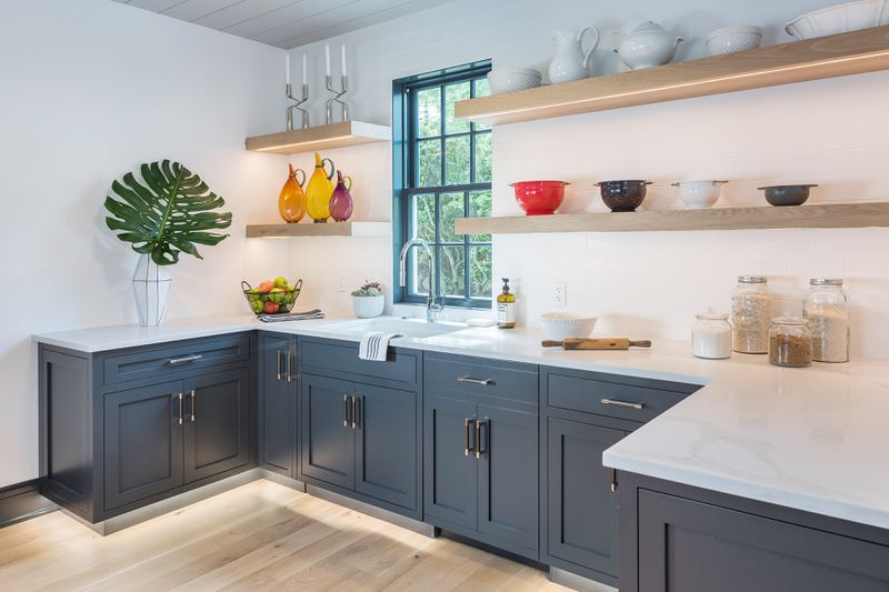 A kitchen with shaker style cabinets and open shelving. 