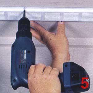 Person using a drill to install a soffit vent.